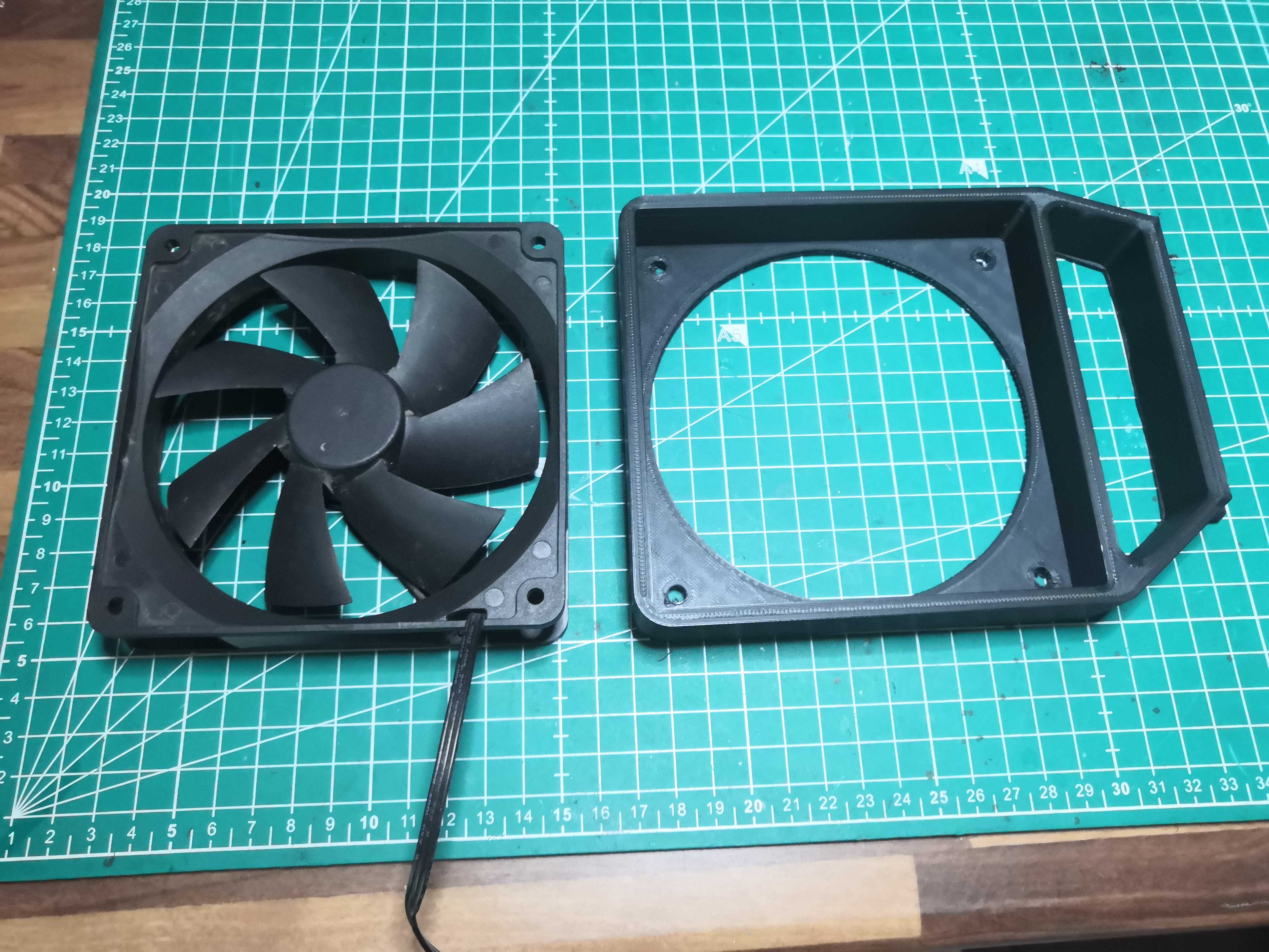 120mm fan and bracket side by side on a cutting mat